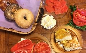 Ruthie Cohen says Jewish soul food "tastes like home." Foods pictured here include (clockwise from top left) bagels, cream cheese, lox, tomatoes, kugel, and a hearty sandwich. | Photo by Ruthie Cohen