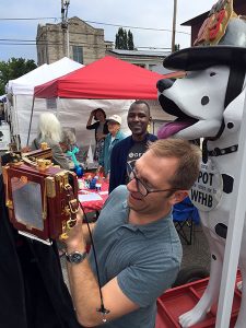 Photographer Adam Reynolds sets up a photo at the 4th Street Festival of Arts and Crafts as Ron Bronson from WFHB looks on. | Limestone Post
