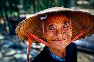 Despite living through years of hardship under the French, the Americans and their Vietnamese allies, and, more recently, conflicts with China, a vendor in a market in the coastal city of Hoi An has a ready smile for customers. She wears the nón lá — a conical hat made of palm leaf and worn by Vietnamese of all ages and both genders. | © Steve Raymer / National Geographic Creative