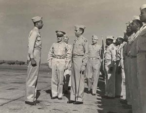 An official U.S. Army Air Forces photo of Colonel Robert R. Selway Jr. (center) reviewing the 618th Bomber Squadron, which is part of the 477th, at the Atterbury Army Air Field in Indiana on June 24, 1944. The Tuskegee Airman that Colonel Selway is facing is Hubert L. Jones. Selway would later segregate the officers's club by designating all black officers as trainees. | Public domain