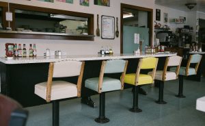 Old men yukking it up at a diner shows that “deep down inside, we’re all 12-year-olds who need something solid and predictable in our lives,” writes Troy Maynard. | Photo by adrian on Unsplash