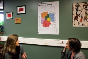 Baynes and Brinegar explain a map posted on their wall, which visualizes what Positive Link services are available to those who live in every county throughout Indiana. | Photo by Nicole McPheeters