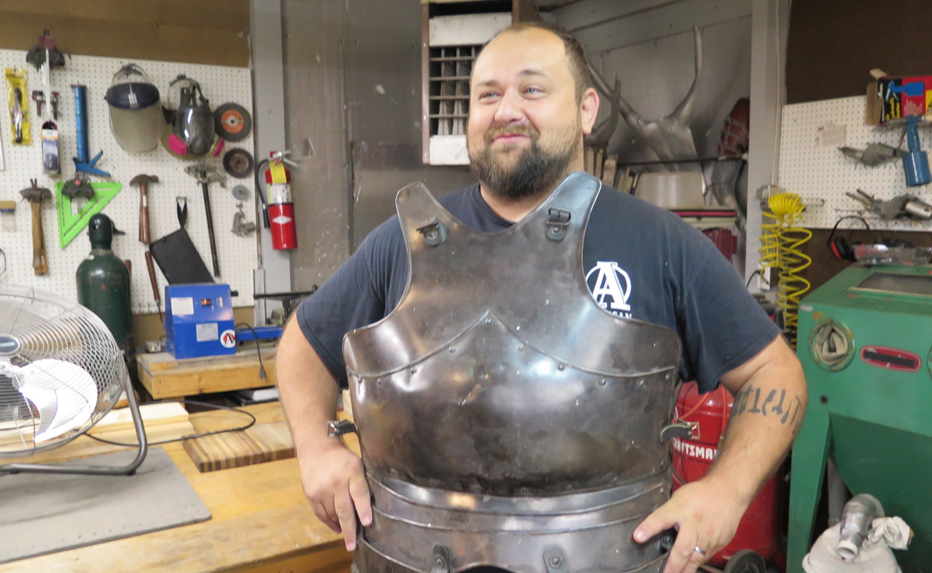 Adam Nahas in Burl and Ingot Tool Library showing a piece of armor that he made. The Tool Library is part of Artisan Alley, the collective art space, studio, workshop, computer lab, gallery, and other projects that began in Nahas’s basement more than a decade ago. | Limestone Post