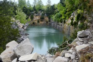 In 2016, Indiana Limestone Company (ILC) gave Limestone Post a tour of iconic Rooftop Quarry in southern Monroe County to show the actions the company took to make the popular swimming hole inaccessible to trespassers, such as bulldozing debris to the top edges of the quarry. In 2018, ILC filled in the quarry with stone and dirt to use as a staging site for stacking blocks of stone. | Photo by Lynae Sowinski
