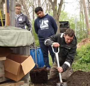 Simon Normile (right) demonstrates the proper way to plant a tree at a CanopyBloomington tree planting in the Maple Heights neighborhood.