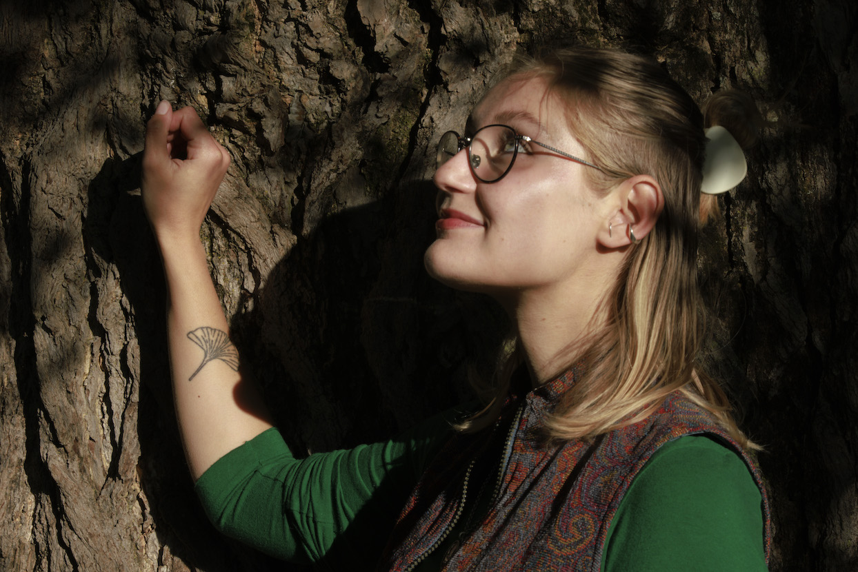 Hannah Gregory, next to a ginkgo tree, shows her tattoo of a ginkgo leaf. | photo by Jeremy Hogan