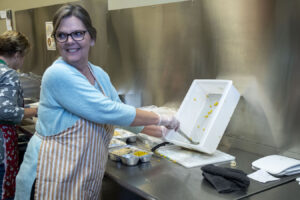 A volunteer fills a take-home meal at Community Kitchen. | Photo by Olivia Bianco