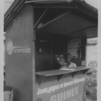 Guinee Games, Conakry, Guinea, 2009, Gelatin Silver Print. Man sells lottery tickets out of a corrugated tin shack.