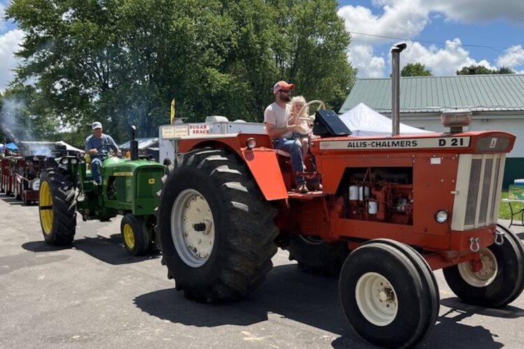 Three generations of tractor enthusiasts ride in the parade at the Monroe County Antique Machinery Association Show in May. Eleanor, 3, sits with her father, Zach Clark, on the Allis-Chalmers while her grandfather Joel Clark follows on the John Deere. | Photos by Limestone Post