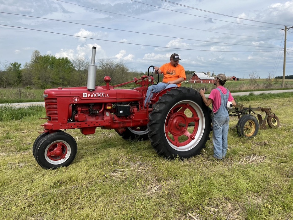 Dylan Chandler (on the 1942 Farmall tractor) talks with Mike Hughes during plow day.