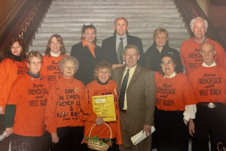 Beginning in the mid-1990s, a group of Orange County citizens wearing orange T-shirts encouraged Indiana lawmakers to grant a gaming license to French Lick. Above, some of the “Orange Shirts” pose for a photo at the Statehouse (l-r): (front row) Betty Oakley, Mary Gilliatt, Geneva Street, Rep. Tom Saunders, Willa Sanders, and Leon Sanders; (back row) Debby Gilliatt, Vicky Perambo, Adina Cloud of the French Lick Springs Resort, Steve Ferguson of Cook Group, Tina Conner of Historic Landmarks, and Jack Carnes. | Photo from the Carnes Family Collection